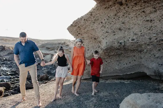 Family beach walk Tenerife - dad leading children through volcanic stones