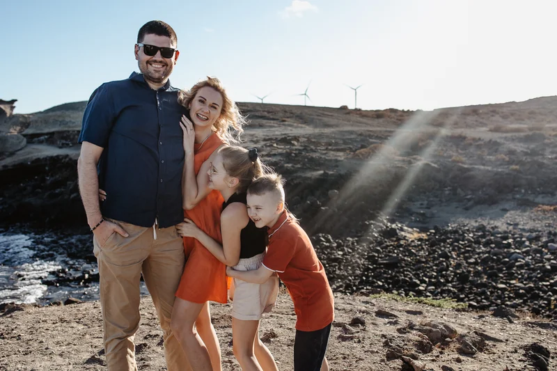 Sesión familiar con molinos de Tenerife - padres con niños con turbinas eólicas de fondo