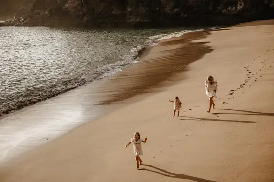 Matka z dwiema córkami bawiące się na piaszczystej plaży Abama Beach