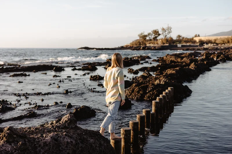 Mujer caminando piscinas naturales Tenerife formaciones volcánicas océano sesión fotográfica