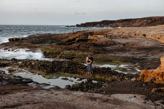 Woman standing alone on dramatic volcanic rock formations Tenerife coastal landscape