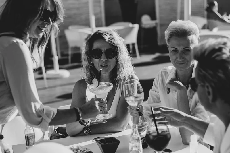 Black and white portrait of women with cocktails during elegant conversations at party