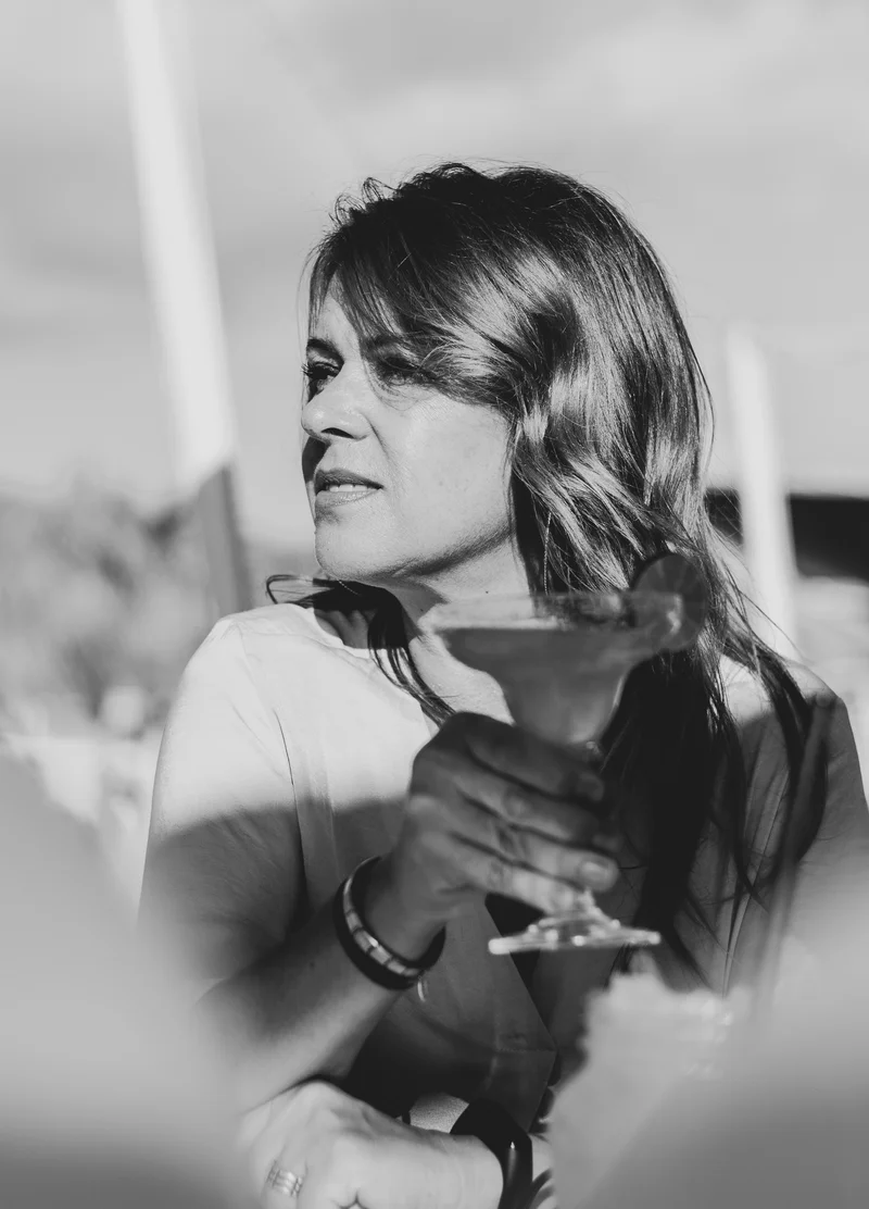 Black and white portrait of woman with cocktail in contemplative moment during elegant party