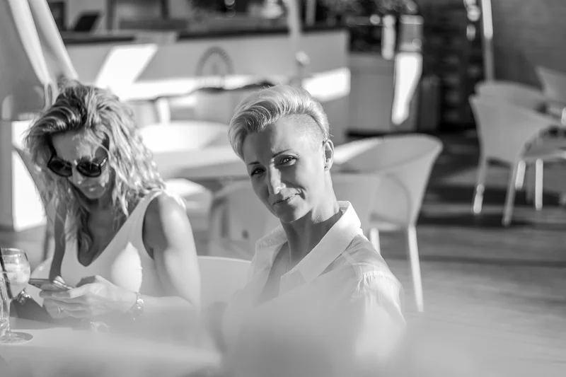 Black and white portrait of two smiling women with wine glasses during social gathering