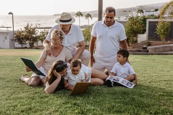 Familia multigeneracional leyendo libro juntos en césped del parque de Tenerife
