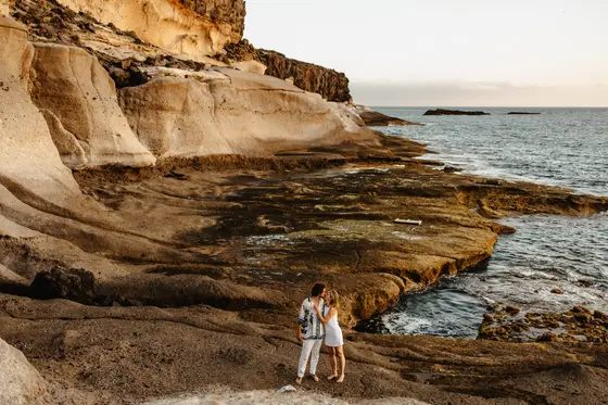 Pareja posando en rocas volcánicas durante sesión de fotografía familiar naturaleza Tenerife salvaje