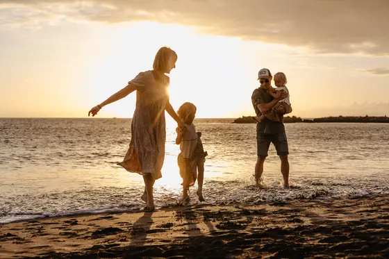 Family silhouettes on beach during sunset in documentary lifestyle photography style