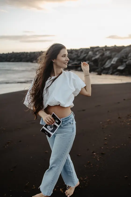Carefree movement pose of pregnant woman with flowing hair on beach