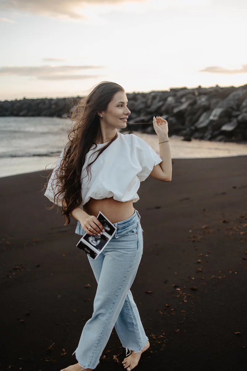 Pose de movimiento despreocupado de mujer embarazada con cabello suelto en la playa