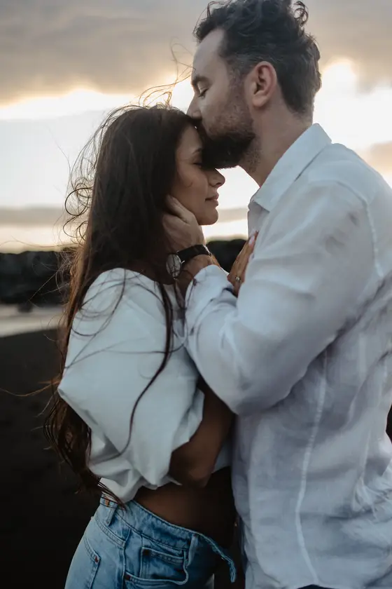 Romantic couple closeness with tender hand-to-face gesture during sunset