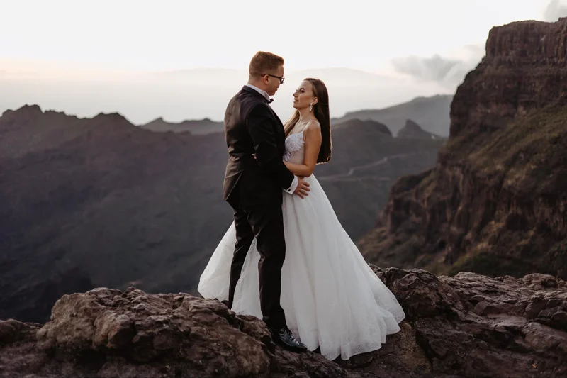 Para podczas elopement wedding na Teneryfie spaceruje po skalistym wybrzeżu z oceanem w tle