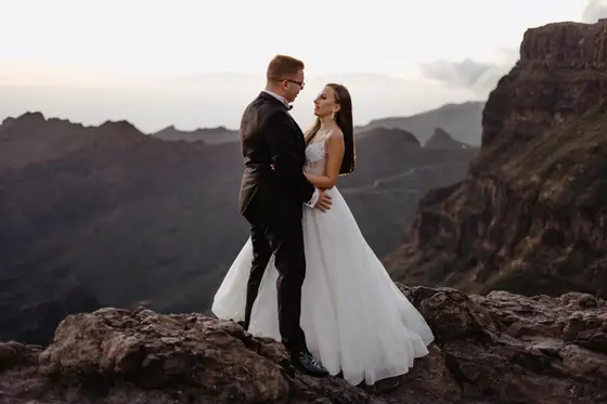 Pareja durante una boda elopement en Tenerife caminando por una costa rocosa con el océano de fondo