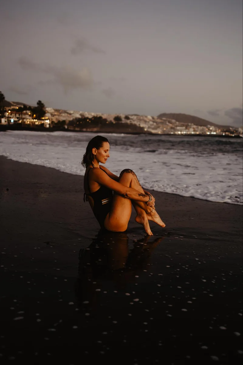 Woman sitting by the ocean during a calm portrait session