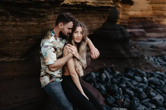 Pareja sentada en rocas junto al océano durante una sesión natural para dos