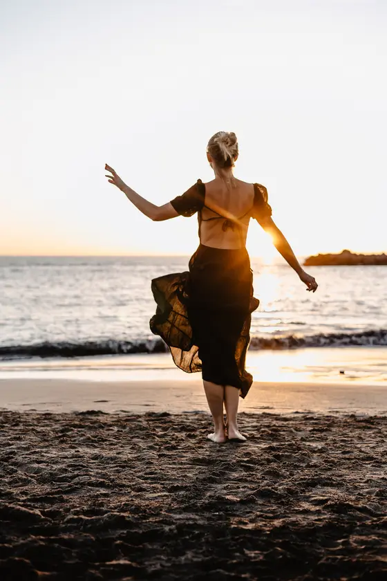 Dynamiczny portret tańczącej kobiety na plaży podczas zachodu słońca na Teneryfie
