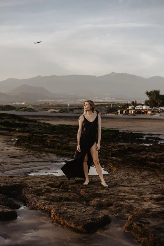 Karolina Chapko en dramática playa rocosa El Médano con avión en cielo y montañas Tenerife de fondo