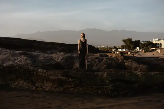 Karolina Chapko con vestido negro posando en paisaje volcánico de El Médano con montañas de Tenerife de fondo