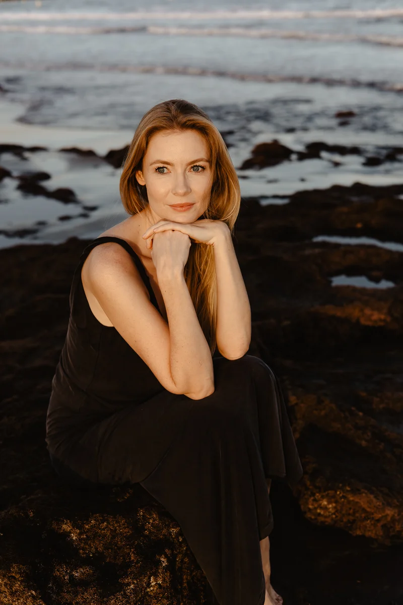 Intimate portrait of Karolina Chapko sitting on volcanic rocks of El Médano with ocean in background during golden hour