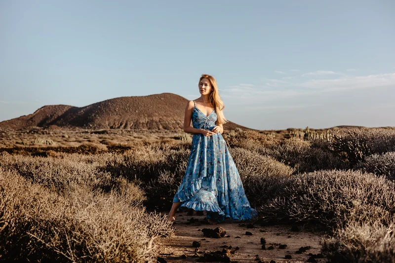 Karolina Chapko posando en vestido azul en sendero a través del paisaje volcánico de Tenerife