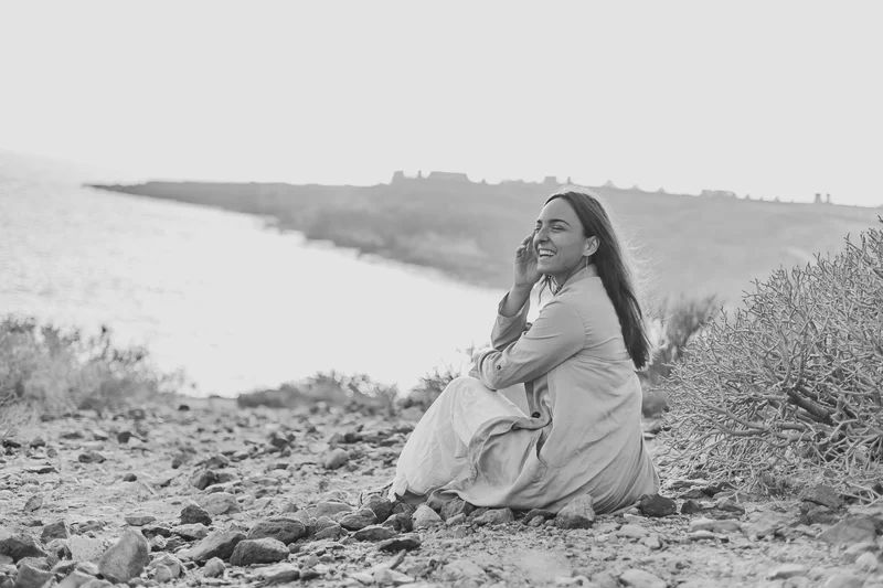Foto en blanco y negro de mujer riendo contra telón dramático del paisaje La Caleta