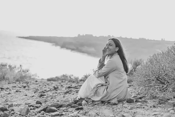 Foto en blanco y negro de mujer riendo contra telón dramático del paisaje La Caleta