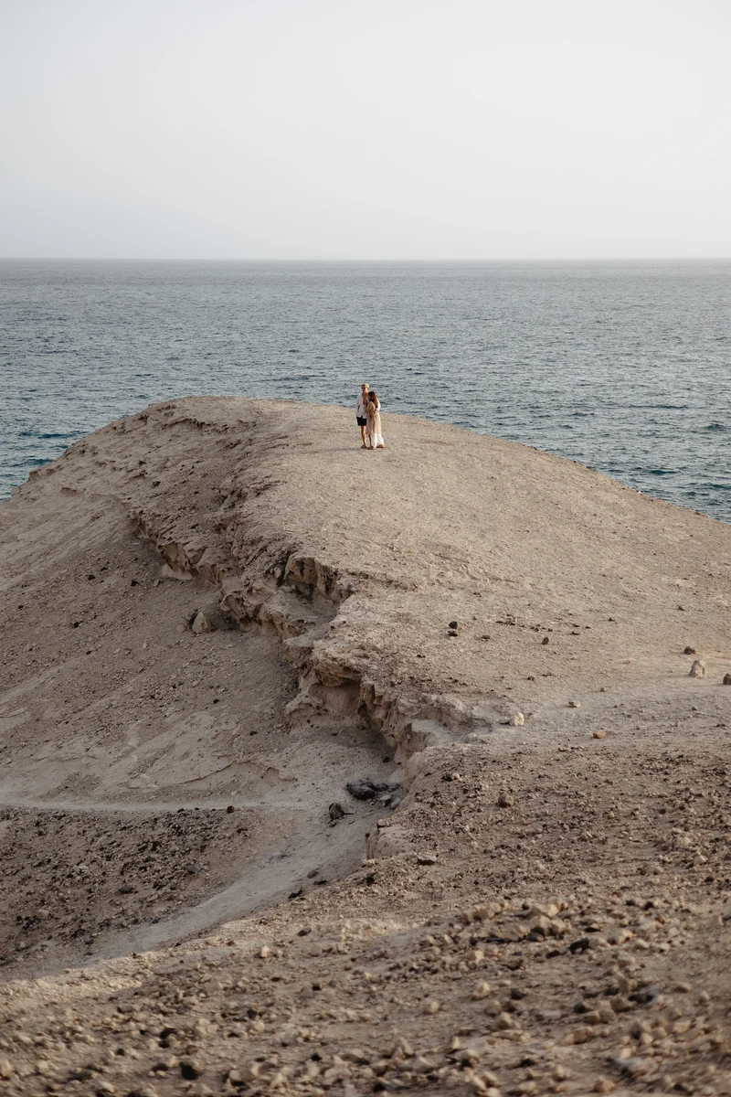 Mujer de pie sola en un acantilado alto sobre el océano durante sesión fotográfica en La Caleta