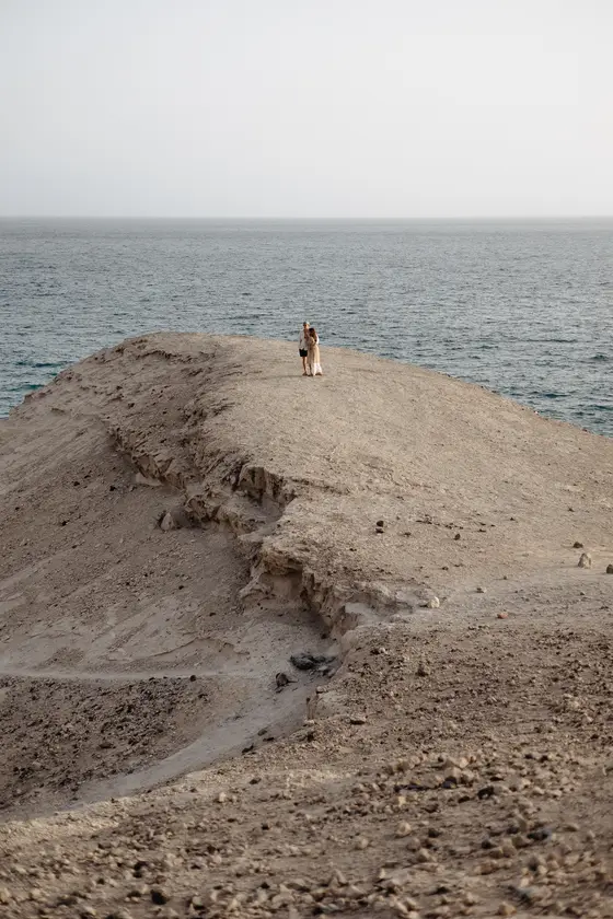 Mujer de pie sola en un acantilado alto sobre el océano durante sesión fotográfica en La Caleta