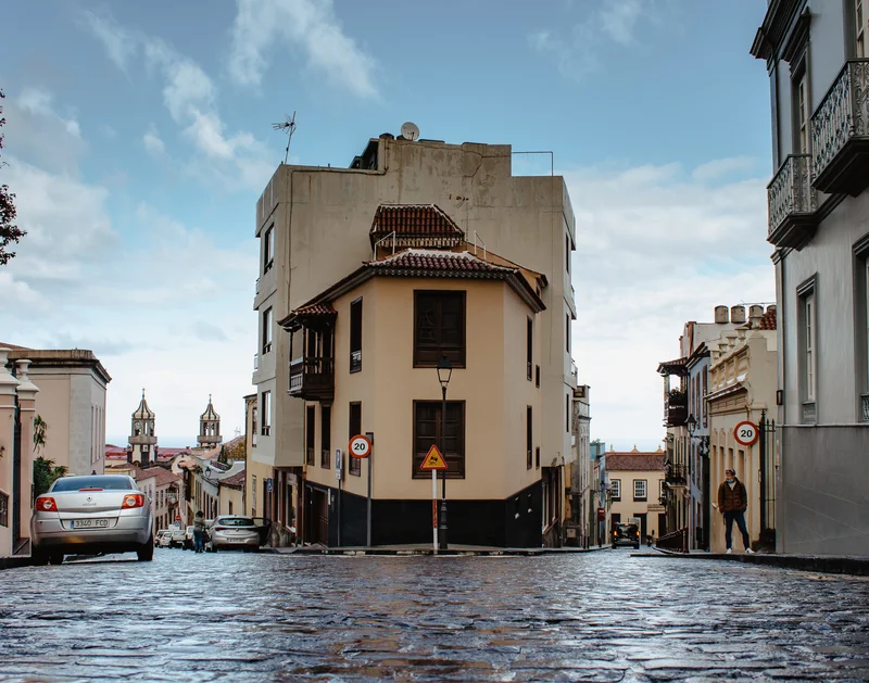 Edificio histórico característico en esquina de La Orotava con balcones canarios tradicionales y adoquines mojados
