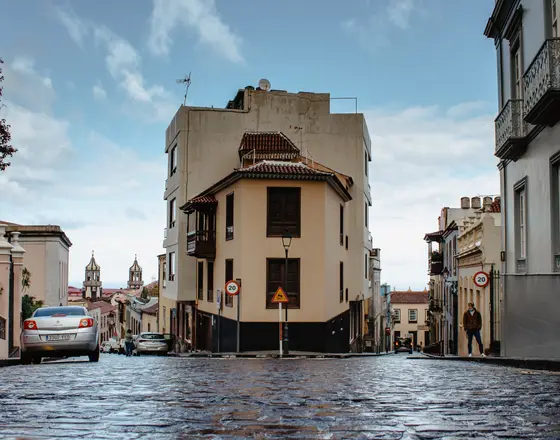 Characteristic historic corner building in La Orotava with traditional Canarian balconies and wet cobblestones