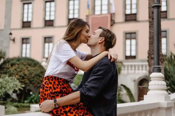 Romantic kiss of couple on white balustrade with historic La Orotava architecture in Tenerife background