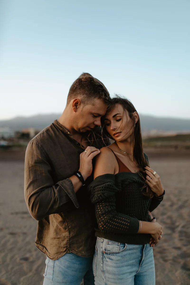 Momento delicado de cercanía de pareja en playa La Tejita con montañas en la distancia