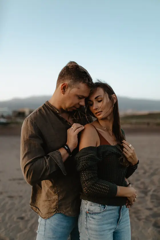 Momento delicado de cercanía de pareja en playa La Tejita con montañas en la distancia