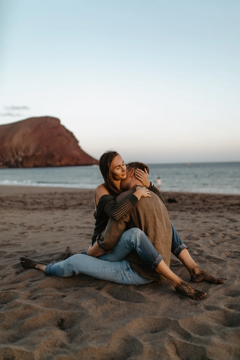 Momento íntimo de pareja en playa La Tejita con Montaña Roja de fondo
