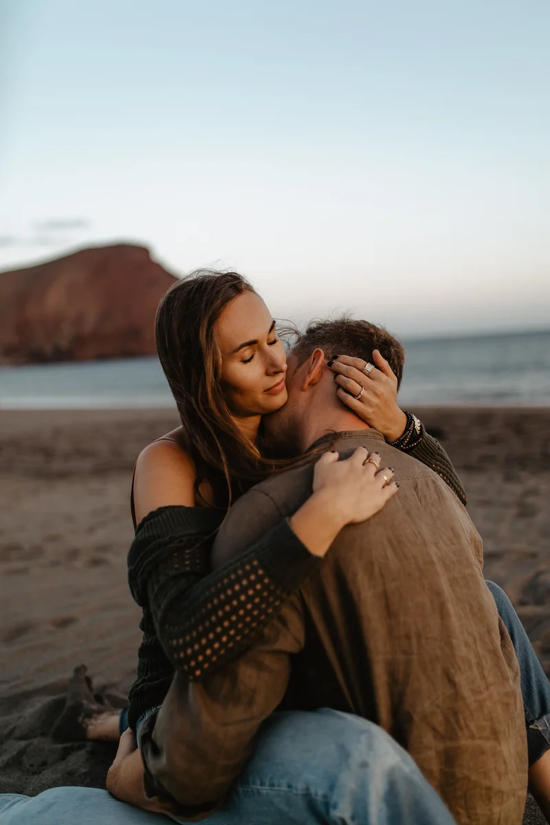 Abrazo tierno de pareja en playa La Tejita con vista a Montaña Roja