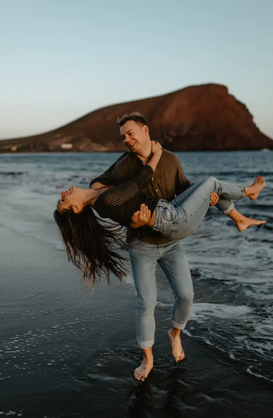 Pareja enamorada jugando en el agua del océano en playa La Tejita con Montaña Roja