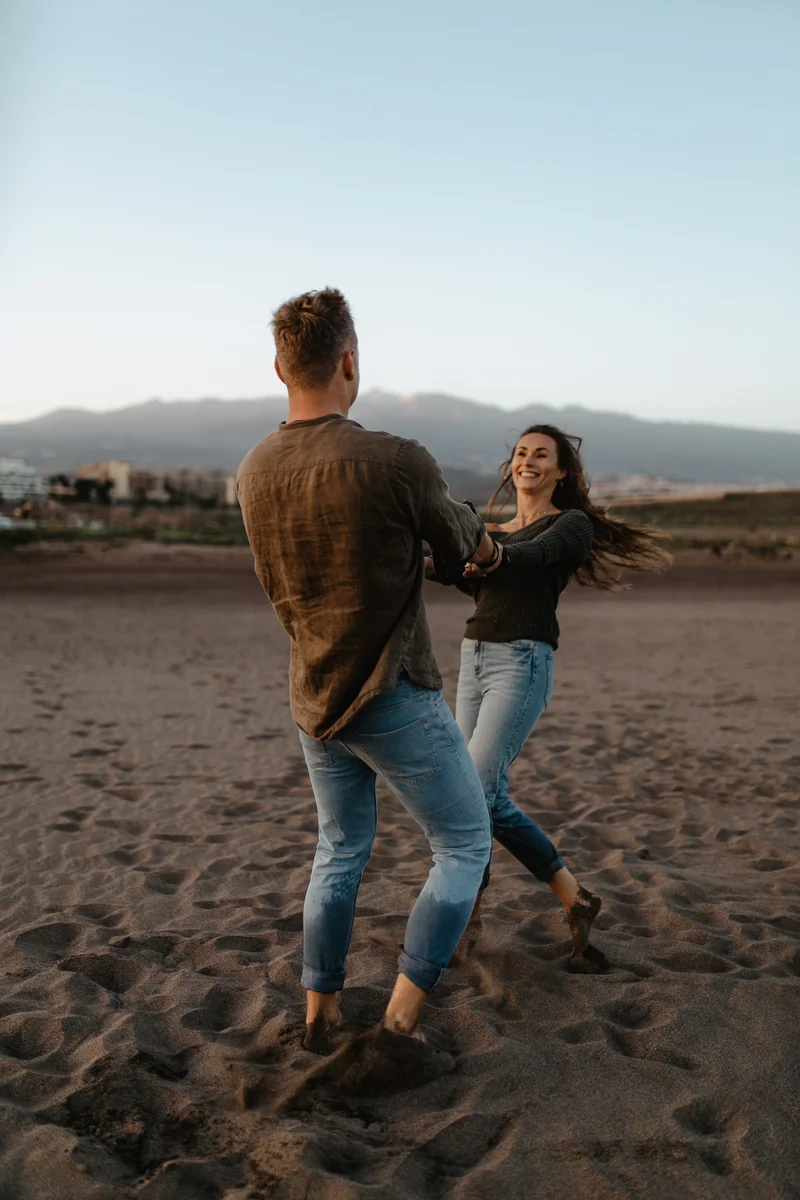 Pareja bailando en arena volcánica negra en playa La Tejita