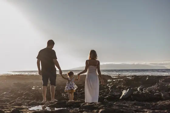 Rodzina trzymająca się za ręce podczas sesji na plaży Las Americas na Teneryfie o zachodzie słońca