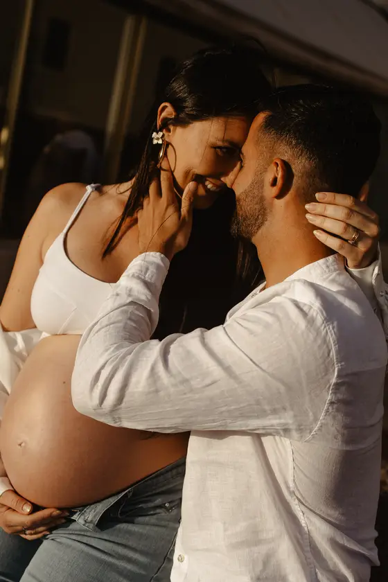 Momento íntimo de pareja esperando bebé en cálida luz dorada durante sesión de maternidad en Las Galletas
