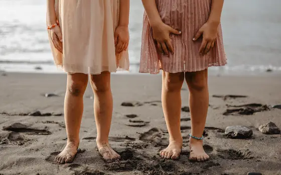Children's bare feet on black volcanic sand of Los Gigantes beach