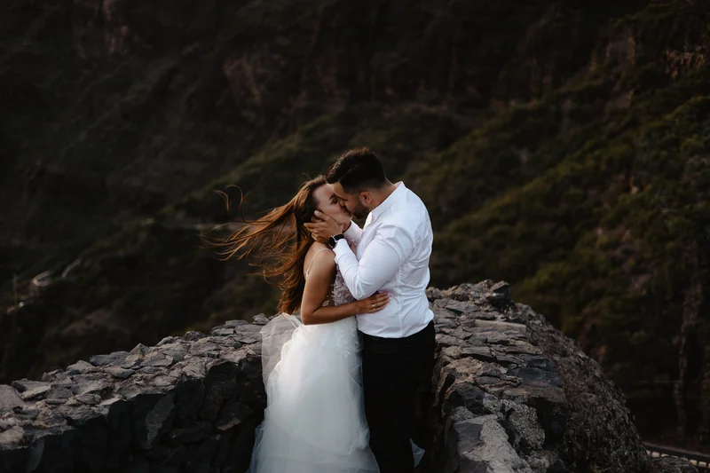 Masca wedding photography intimate couple moment on stone cliff with mountain landscape backdrop