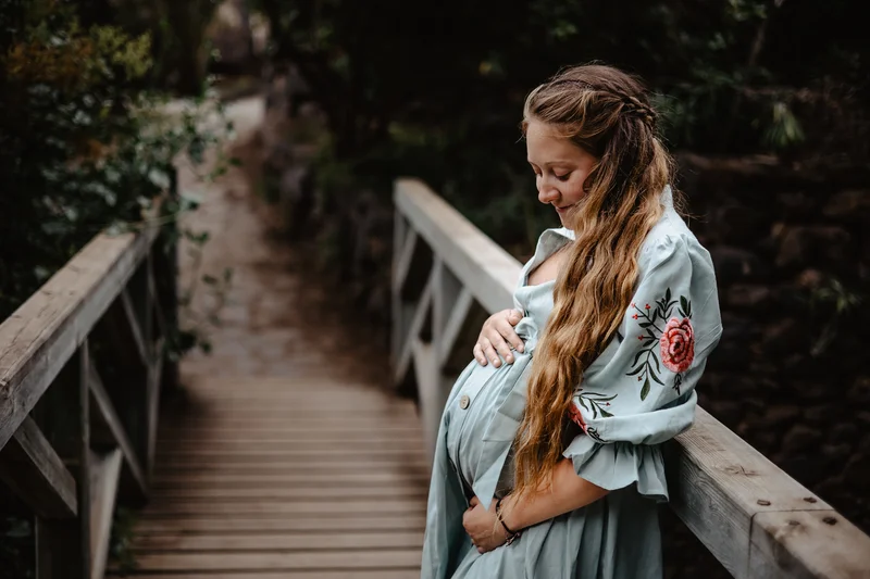 Expecting mother on wooden bridge caressing baby bump during maternity photoshoot session