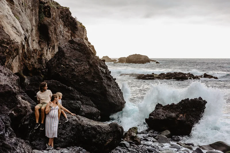 Expecting parents couple on Tenerife cliffs with dramatic crashing ocean waves backdrop