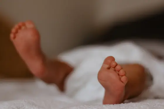 Tiny newborn baby feet on white blanket during newborn photography Tenerife session