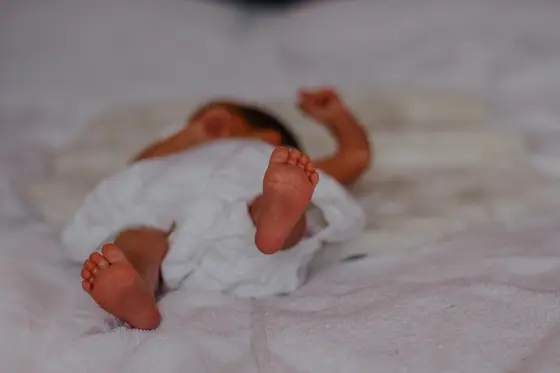 Newborn baby lying on white blanket showing tiny feet during Tenerife photography session