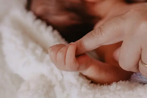 Tiny newborn hands grasping parent's finger during newborn photography Tenerife session