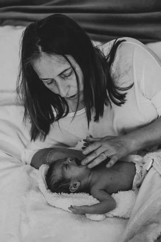 Mother gently touching newborn's face in black and white newborn photography Tenerife
