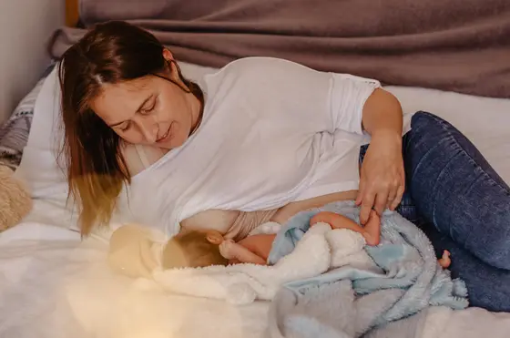 Mother tenderly cuddling newborn on bed during newborn photography Tenerife session