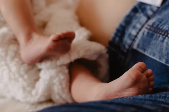 Tiny newborn feet with mother in background during newborn photography Tenerife session