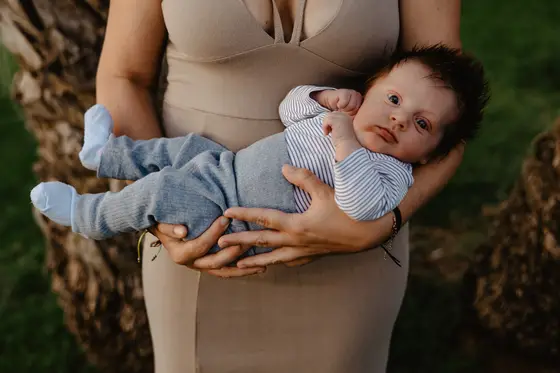 Matka trzyma noworodka w ramionach podczas sesji noworodkowej w plenerze Teneryfa portret