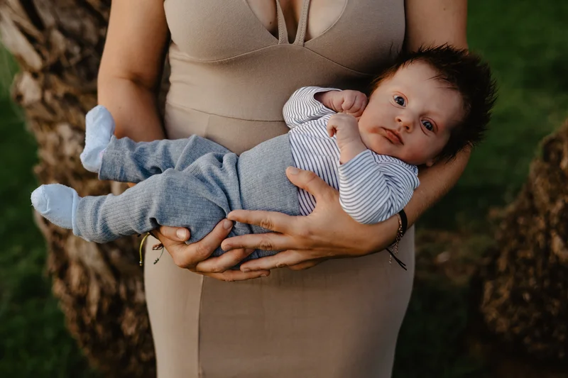 Mother holding newborn in arms during outdoor newborn photography portrait session Tenerife